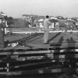 Workmen on top of roof beams 